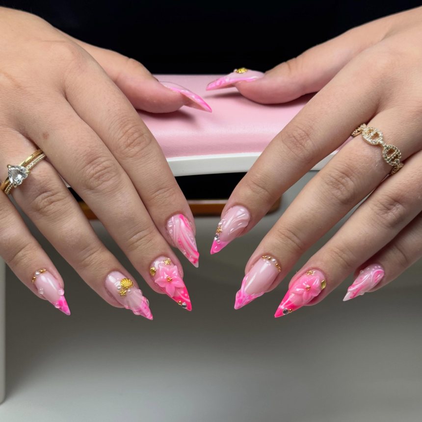 Ongles stiletto roses avec fleurs en 3D et perles dorées